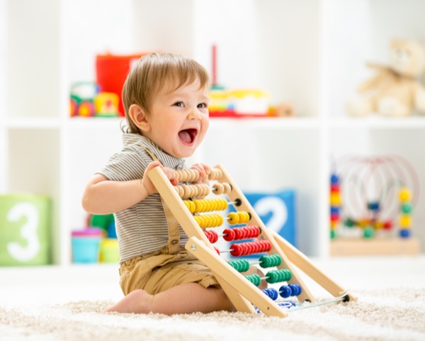 Little child boy playing with toy blocks. Baby in nursery or kindergarten