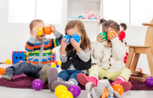kids holding play balls and putting them in front of their eyes in a play room